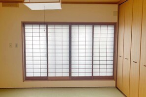 A room with a large shoji screen window, wooden sliding doors, and a tatami mat floor. - Vacation Rental Hanatsusuri Izukogen (Ito)