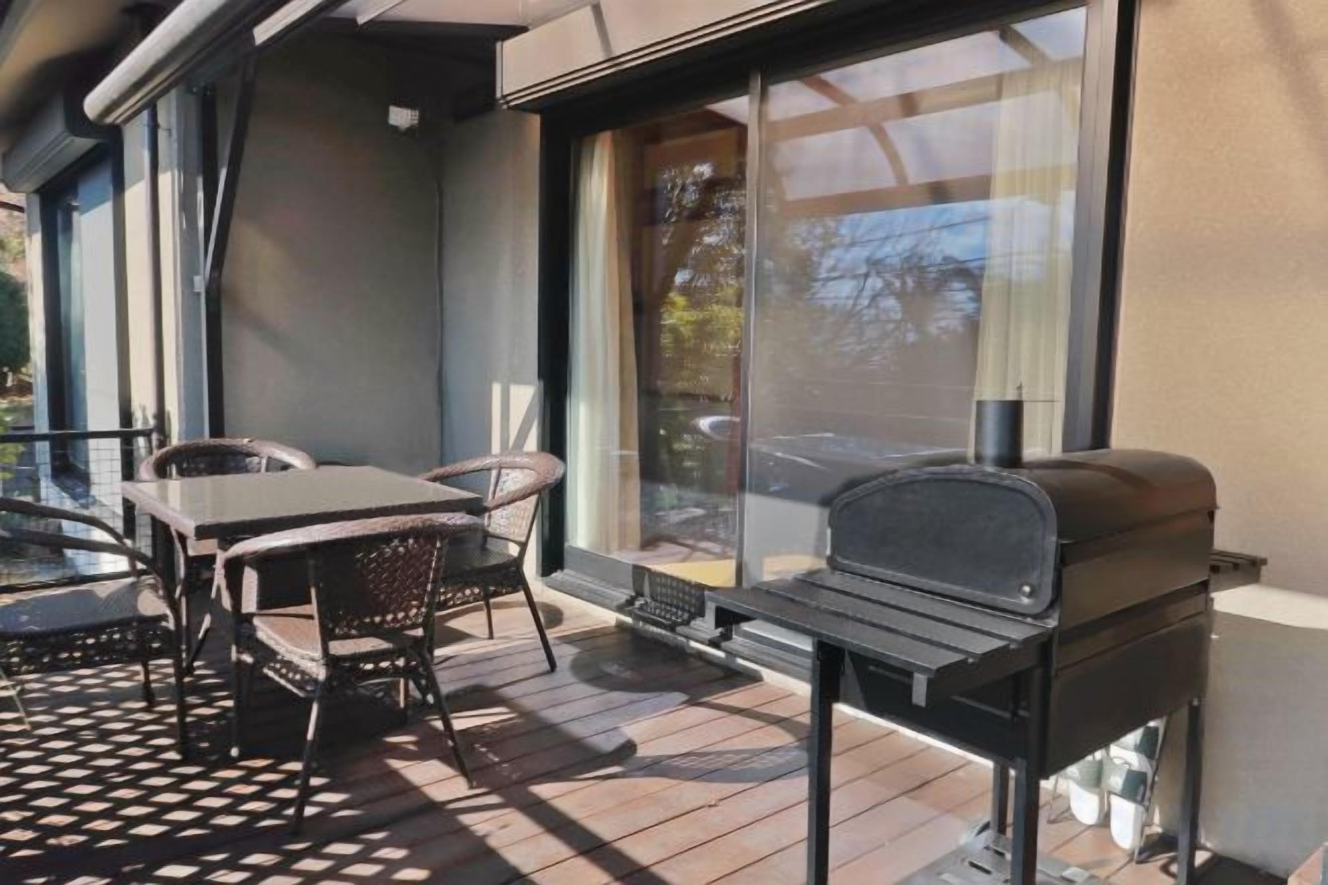 An outdoor patio with a grill, a table, and chairs.