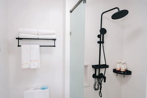 A bathroom with a towel rack, a toilet, a shower with a handheld showerhead, and a shelf with bottles. - Migratory Bird Lake View Inn (Dali City)