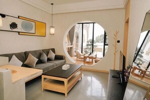 A modern living room with a sofa, coffee table, and a circular window. - Migratory Bird Lake View Inn (Dali City)