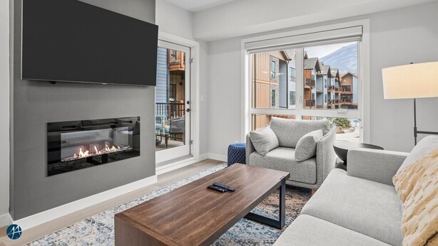 A modern living room with a fireplace, a sofa, a coffee table, and a TV mounted on the wall. - 1 Bed/1 Bath Sparrowhawk-Courtyard Facing-Sleeps 4 (Dead Man's Flats)