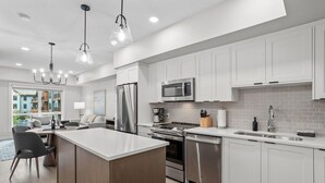A modern kitchen with white cabinets, stainless steel appliances, and a central island. - 1 Bed/1 Bath Sparrowhawk-Courtyard Facing-Sleeps 4 (Dead Man's Flats)