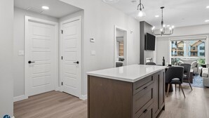 A modern kitchen with a central island, white cabinetry, and pendant lighting. - 1 Bed/1 Bath Sparrowhawk-Courtyard Facing-Sleeps 4 (Dead Man's Flats)