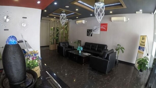 A lobby with a reception desk, black sofas, a coffee table, decorative plants, and a chandelier. - Nine Days Hotel (Batam)