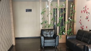 A lobby with a reception desk, a black leather sofa, and a potted plant. - Nine Days Hotel (Batam)