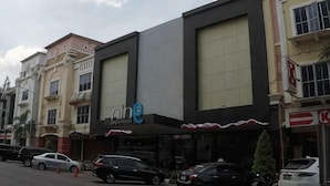 A building with a large sign, a parking lot, and several parked cars. - Nine Days Hotel (Batam)