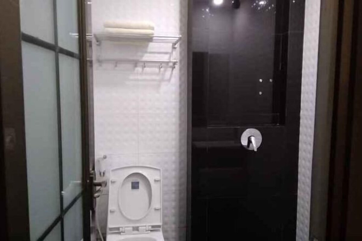 A bathroom with a toilet, a glass partition, and a shower area.
