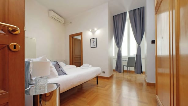 Una habitación de hotel con cama, mesita de noche y vista al pasillo.