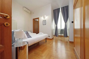 Una habitación de hotel con cama, mesita de noche y vista al pasillo.