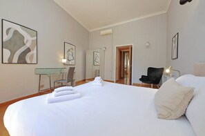 A hotel room with a large bed, a desk with a chair, a black chair, and artwork on the walls. - Flatinrome Exclusive Historic Ghetto  (Rome)