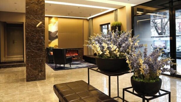 A modern lobby with a marble column, a fireplace, a seating area, and large windows. - Homeinn Selected Hotel (Beijing Normal University Jishuitan Subway Station) (Beijing)