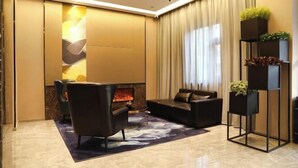 A modern living room with a fireplace, leather sofa, and a black metal shelving unit with plants. - Homeinn Selected Hotel (Beijing Normal University Jishuitan Subway Station) (Beijing)