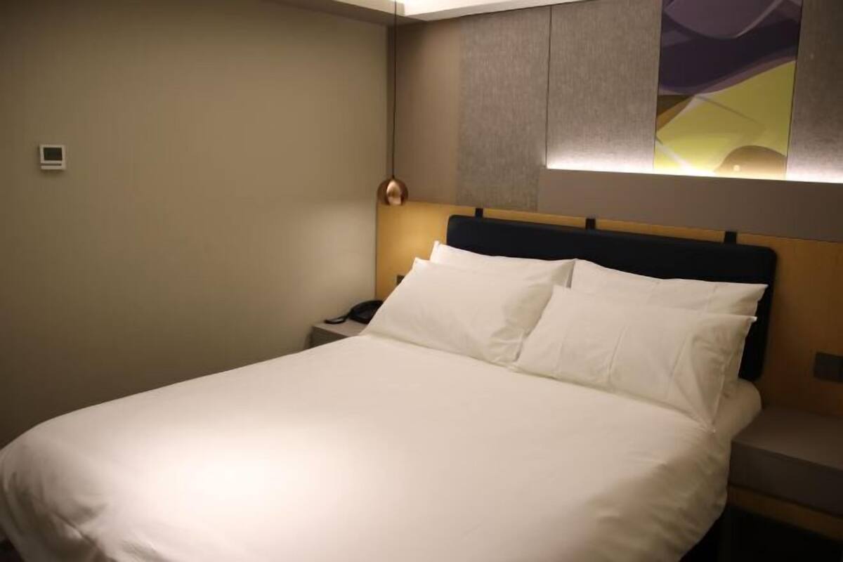 A neatly made bed with white linens in a hotel room.