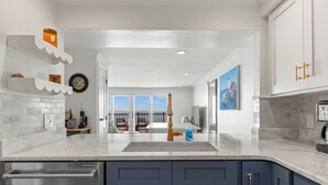 A modern kitchen with white and dark blue cabinetry, a stainless steel dishwasher, and a large island with a sink.