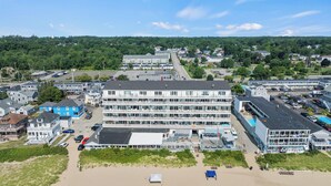 A multi-story hotel with a beach view, parking lot, and adjacent buildings.