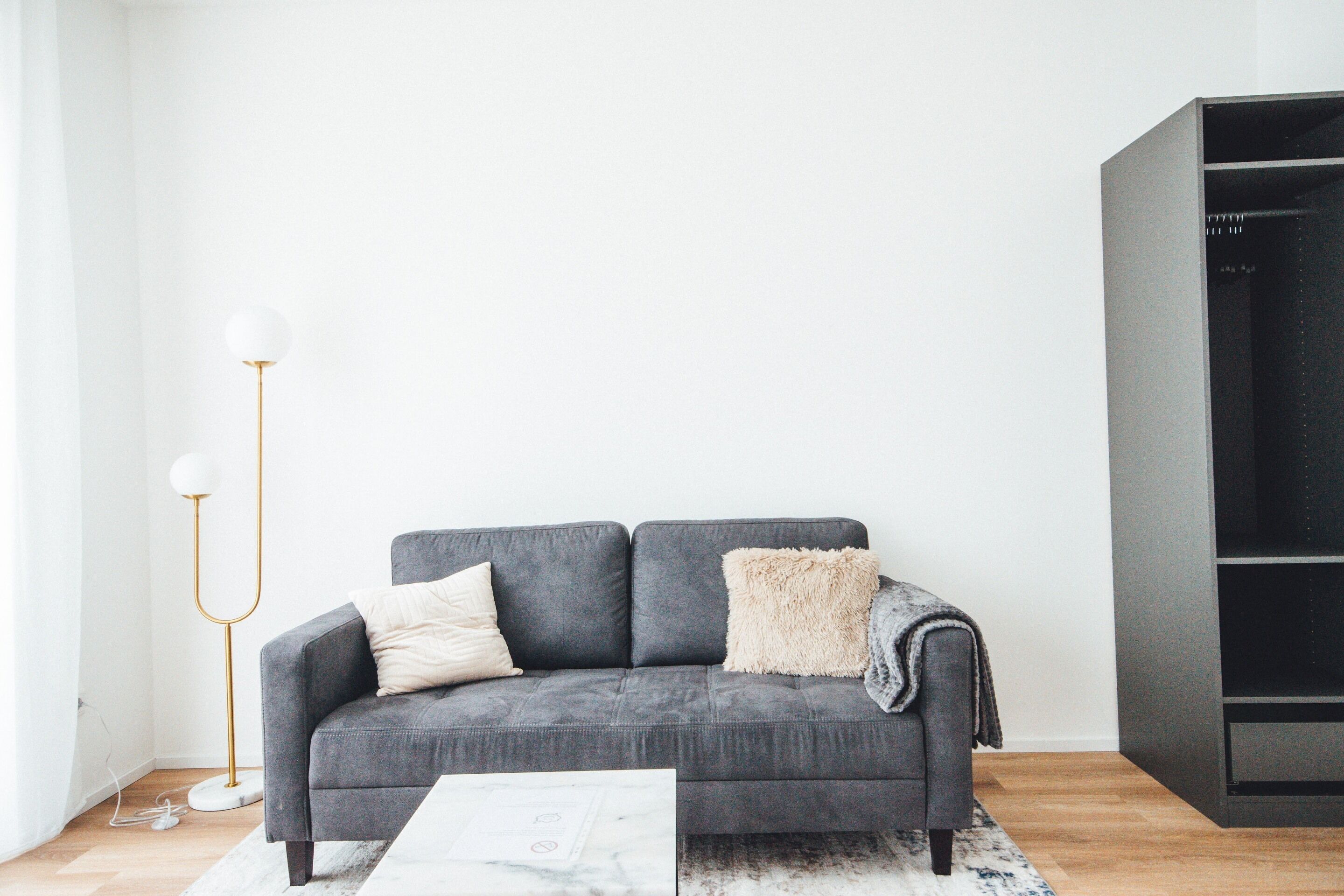 Ein modernes Wohnzimmer mit einer grauen Couch, einem weißen Couchtisch und einem schwarzen Bücherregal.