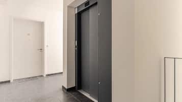 A hallway with a door marked '23' and a modern elevator.