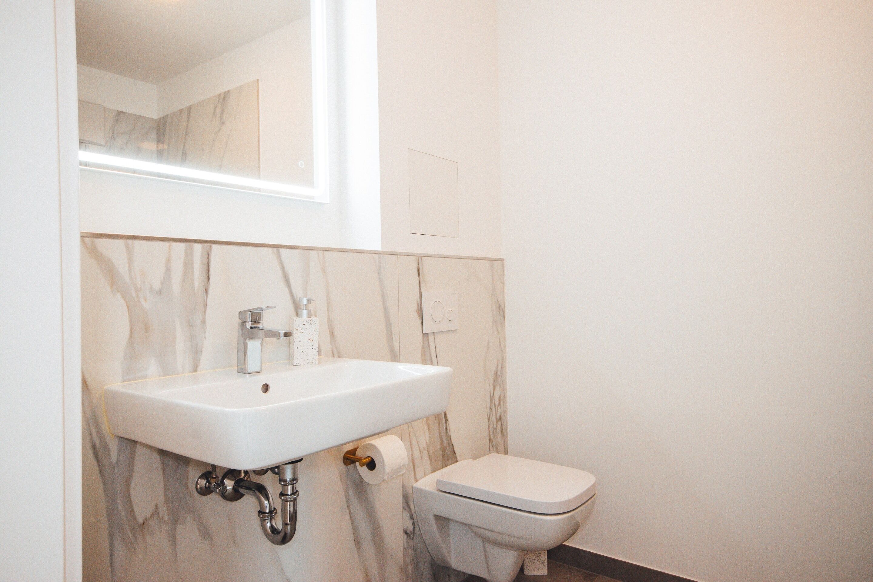 A bathroom with a marble sink, toilet, and a mirror above the sink.