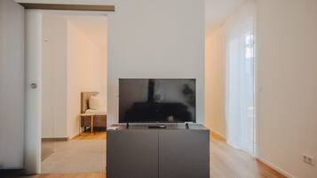 A modern living room with a flat-screen TV on a dark cabinet, a small side table, and a chair.