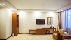 A hotel room with a wooden desk, a television, a mirror, and a sofa. - Yake Shiyuxin Business Hotel (Yakeshi)