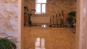 A marble-floored lobby with potted plants and a radiator. - Yake Shiyuxin Business Hotel (Yakeshi)