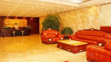 A lobby with leather sofas, a reception desk, and a large plant.