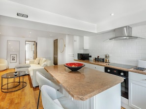Una cocina moderna con gabinetes blancos, encimera de granito y electrodomésticos de acero inoxidable.