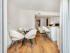Una cocina moderna con microondas, un comedor con mesa redonda y sillas, y una sala de estar con sofá y mesa de centro.