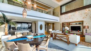 A spacious living area with a large dining table, comfortable seating, a fireplace, and a television.