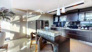 A modern kitchen with a marble countertop, stainless steel appliances, and a large island with bar stools.