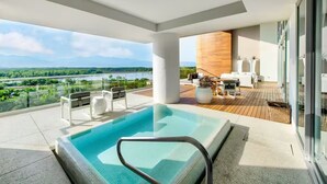 A modern outdoor pool area with a view of a river and mountains.