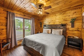 A wooden-paneled bedroom with a bed, a ceiling fan, a window with blinds, and a radiator. - Mountain Views+Hot Tub+Fire Pit+4 Mi to Pigeon Forge (Sevierville)