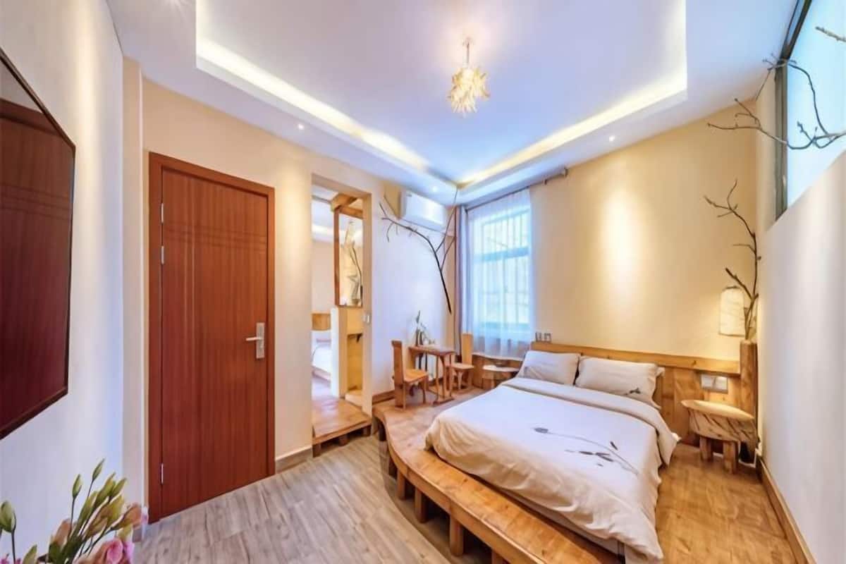 A modern bedroom with a bed, bedside tables, a wooden bench, and a door.