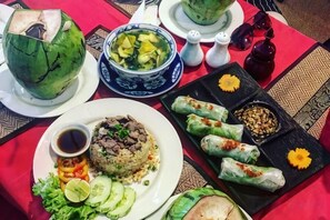 A table with various dishes including a bowl of soup, a plate of rice with meat, and several spring rolls. - Beginner's Mind in Dali Art Theme Hotel (Dali City)