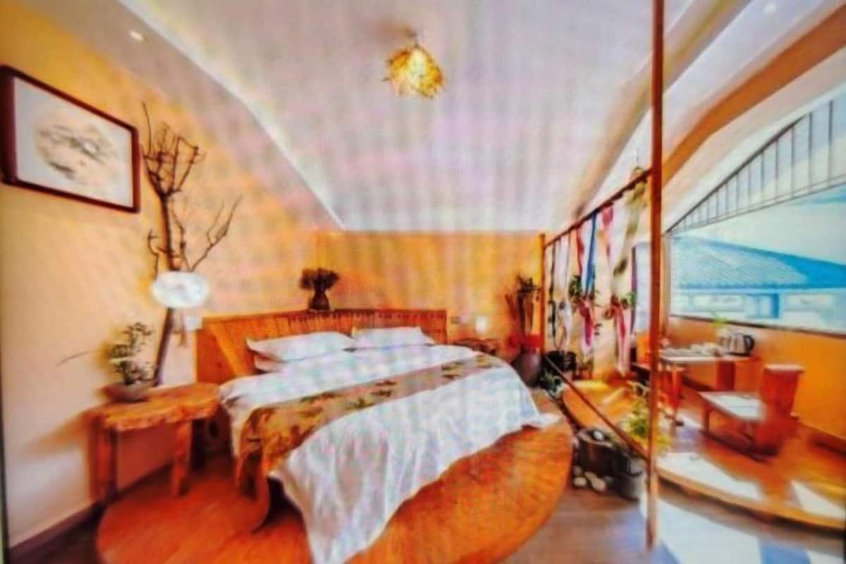 A modern bedroom with a large bed, a bedside table, a lamp, and a view of the outside.