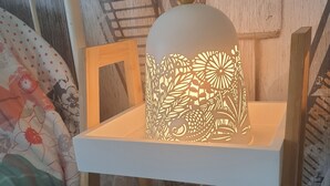 Ein Bett mit weißem Gestell, einem Holz-Kopfteil und einem Nachttisch in Weiß mit dekorativer Lampe.