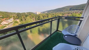 Ein Balkon mit grünem Teppich, einem Metallgeländer und einem weißen Stuhl.