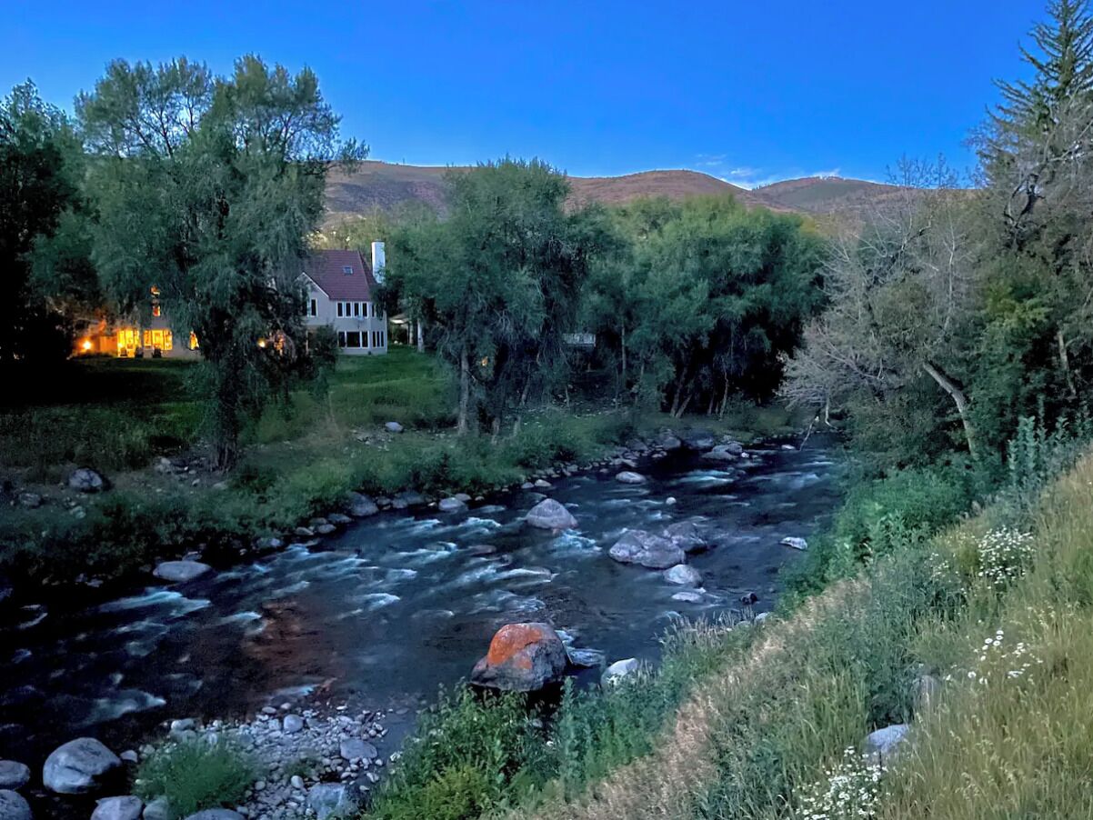 Un río que serpentea por un paisaje con una casa en la orilla izquierda.