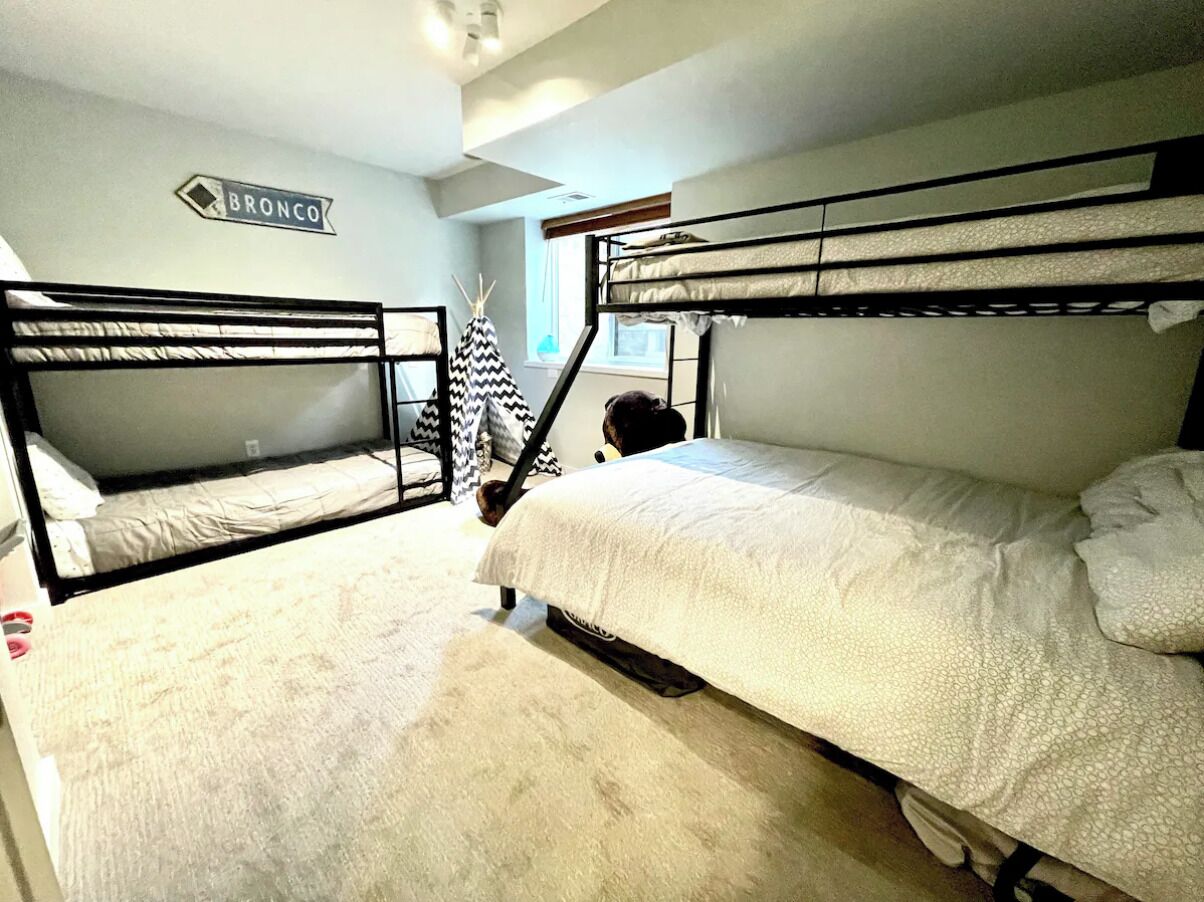 A dormitory-style room with bunk beds, a visible window, and a 'BRONCO' sign on the wall.
