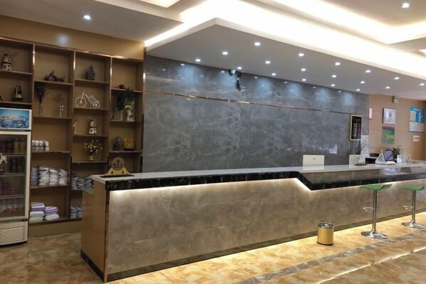 A hotel reception area with a marble counter, shelves with amenities, and a modern design. - Jingxi Wanji Hotel (Jingxi)
