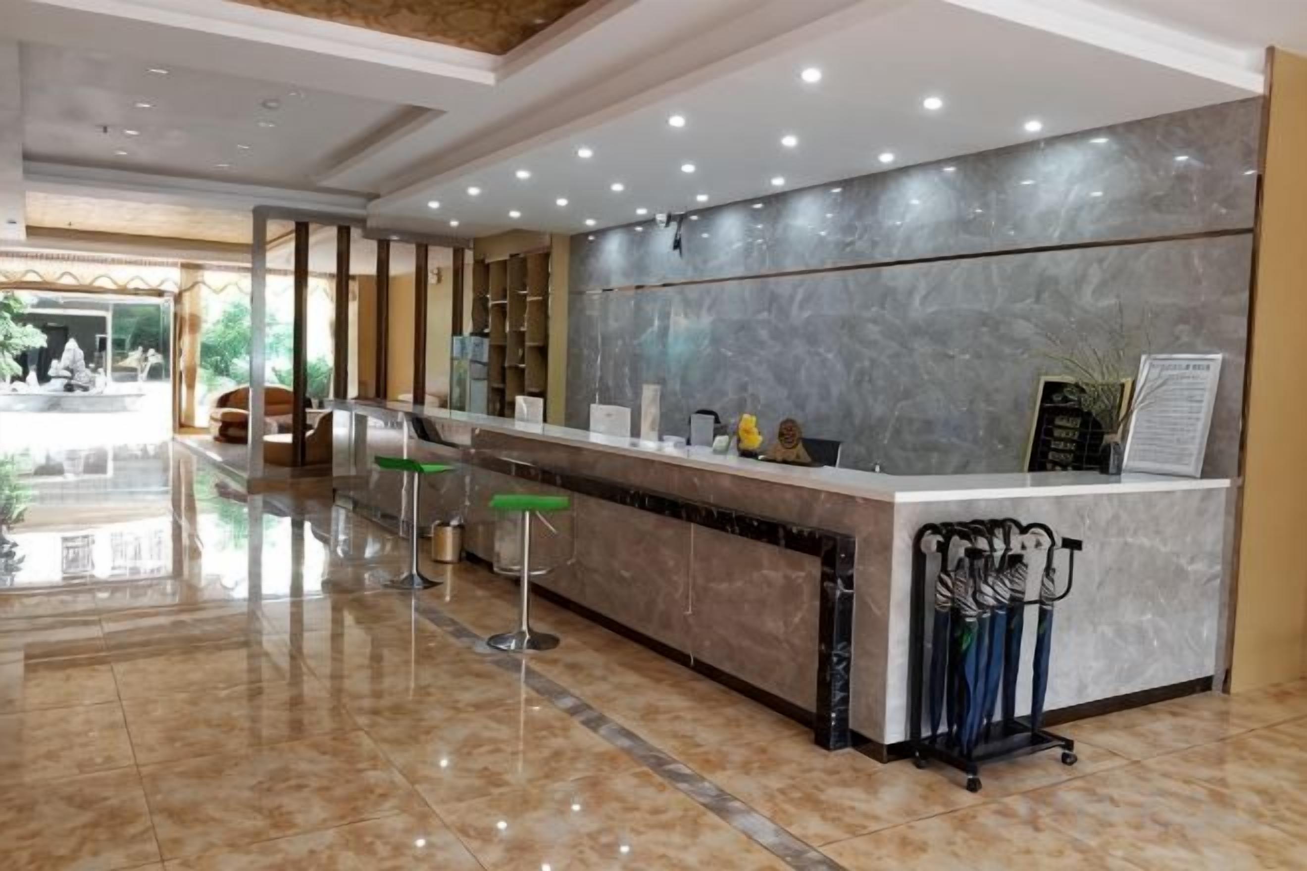 Un espace d’accueil d’hôtel avec un comptoir en marbre, des tabourets de bar et un porte-manteau.