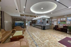 A hotel lobby with leather sofas, a reception desk, and a marble floor. - Jingxi Wanji Hotel (Jingxi)