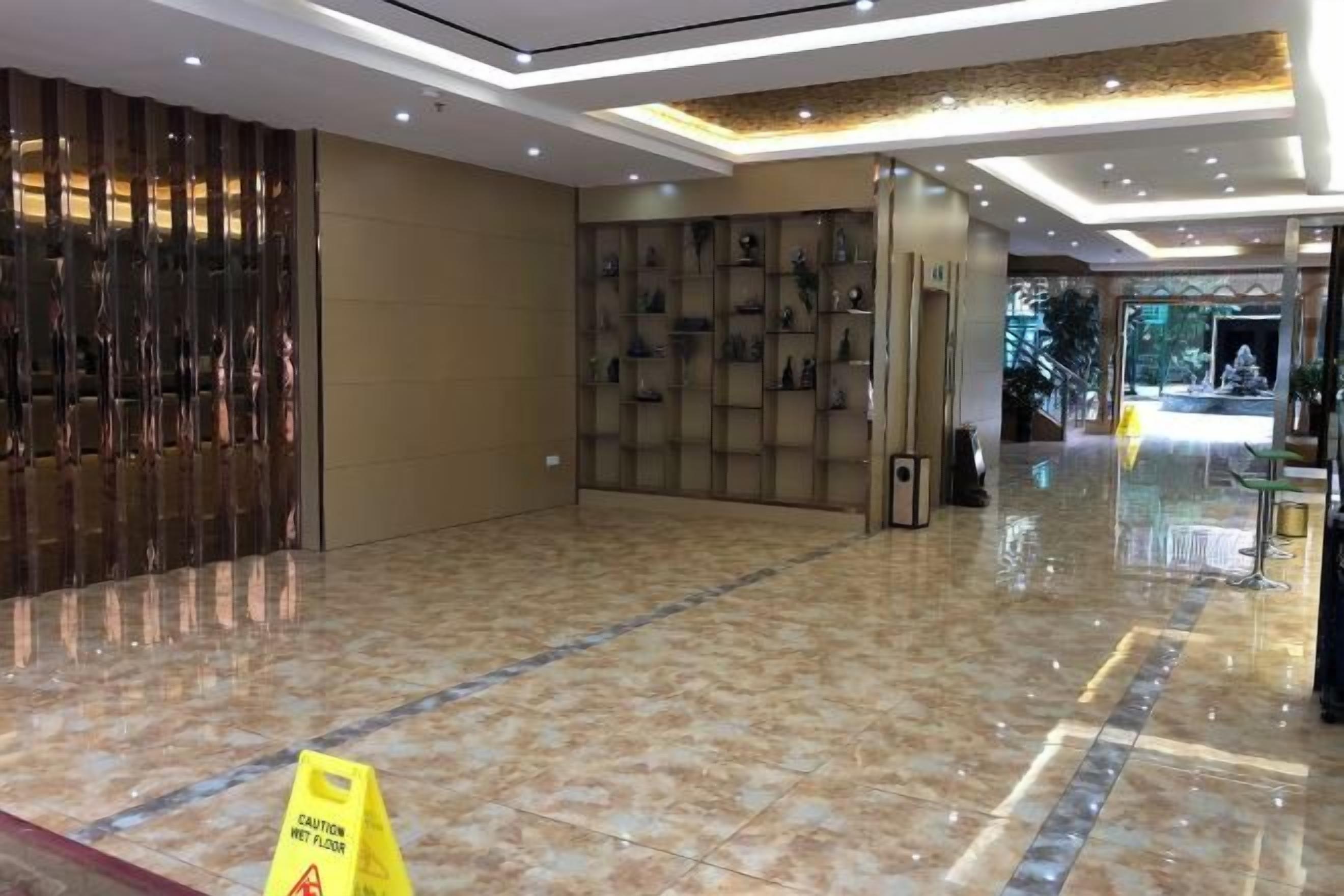 Un vestíbulo de hotel con piso de mármol pulido, una mesa de recepción y una pared con cuadros enmarcados.