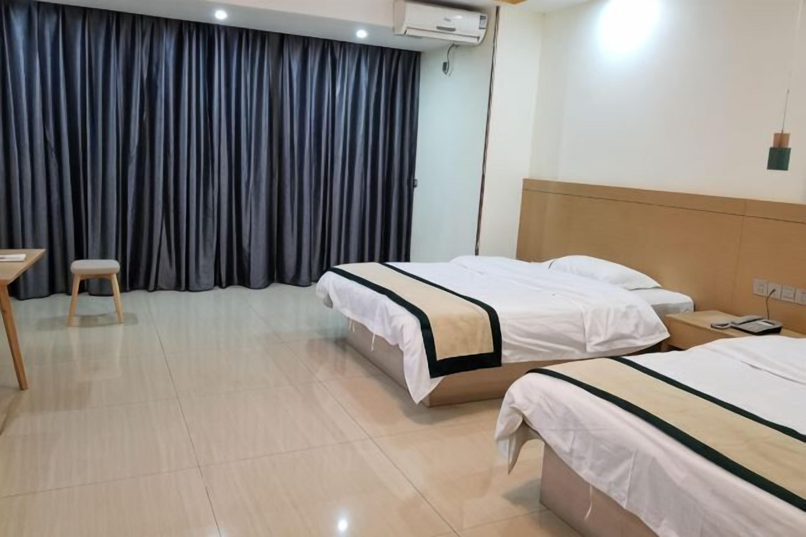 A hotel room with two beds, a desk, a chair, and a large window with curtains.