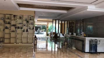 Un vestíbulo de hotel con piso de mármol, una recepción y una pared decorativa.