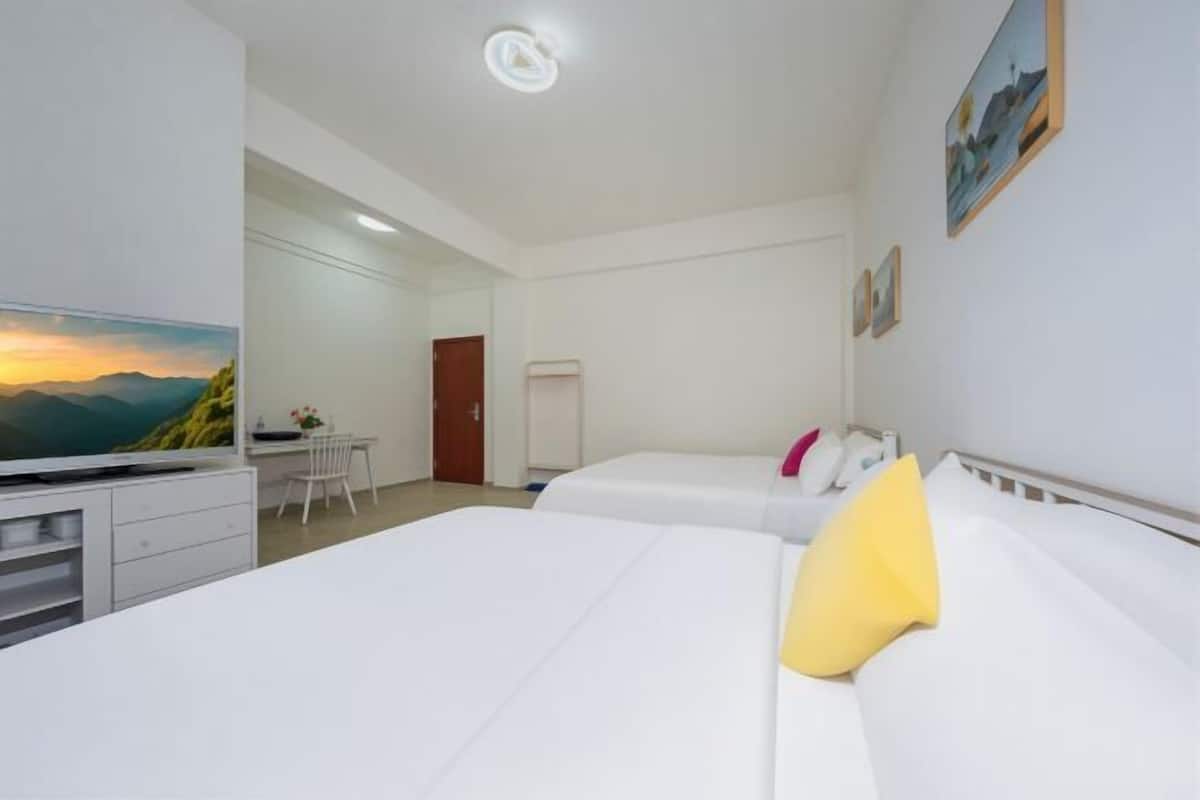 Une chambre d’hôtel avec deux lits, un bureau et une télévision.
