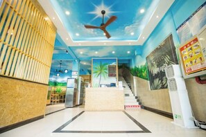A hotel lobby with a reception desk, a staircase, and a ceiling fan. - Nongzai Guesthouse (Sanya Wuzhizhou Island Houhai) (Sanya)