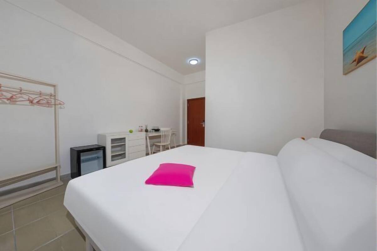 Une chambre d’hôtel avec un lit, un bureau, une chaise et un petit placard.