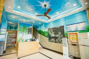 A reception area with a counter, a ceiling fan, a poster, and a vending machine. - Nongzai Guesthouse (Sanya Wuzhizhou Island Houhai) (Sanya)