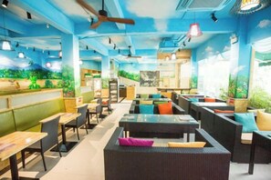 A restaurant interior with high ceilings, ceiling fans, and a variety of seating options including tables and booths. - Nongzai Guesthouse (Sanya Wuzhizhou Island Houhai) (Sanya)